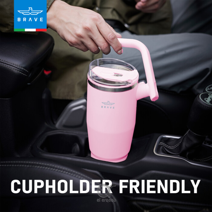 A pink Brave Tumbler Mug with a 180° rotating handle is shown fitting neatly into a car’s cup holder.