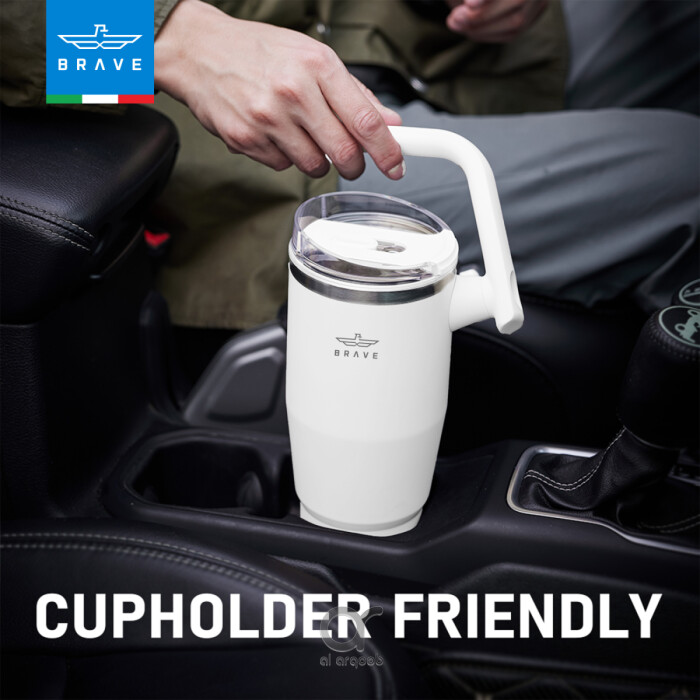 A white Brave Tumbler Mug with a 180° rotating handle is shown fitting neatly into a car’s cup holder.