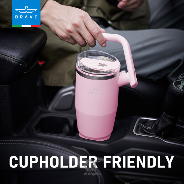 A pink Brave Tumbler Mug with a 180° rotating handle is shown fitting neatly into a car’s cup holder.