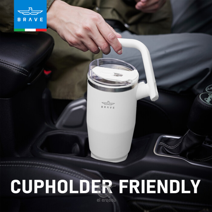 A white Brave Tumbler Mug with a 180° rotating handle is shown fitting neatly into a car’s cup holder.